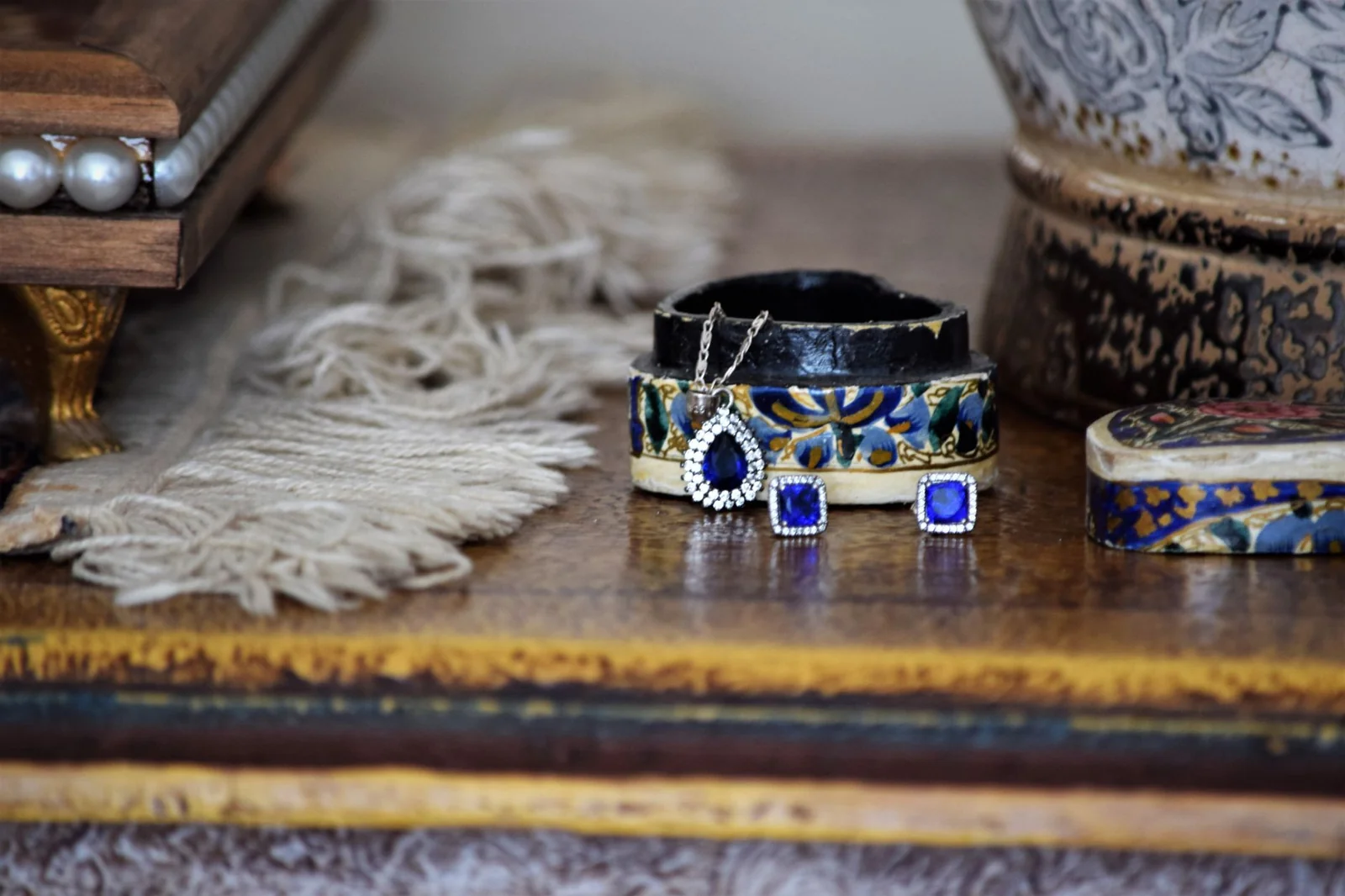 Close-up of elegant jewelry including earrings and pendant on a rustic table setting.
